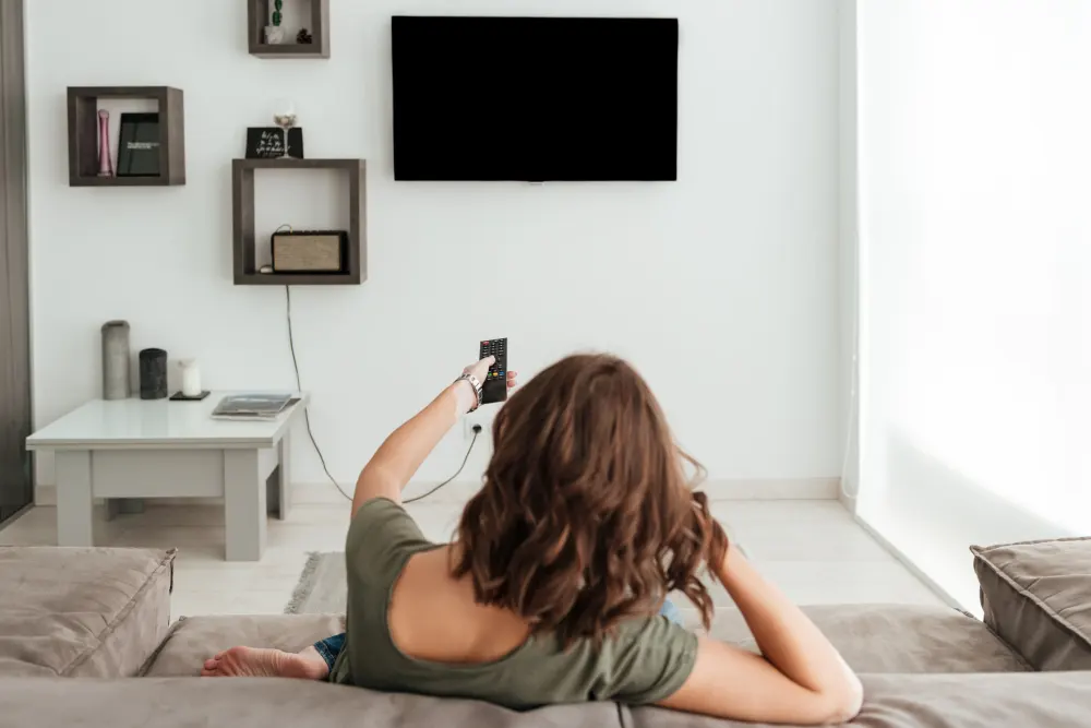 back-view-casual-woman-sitting-sofa-watching-tv-home