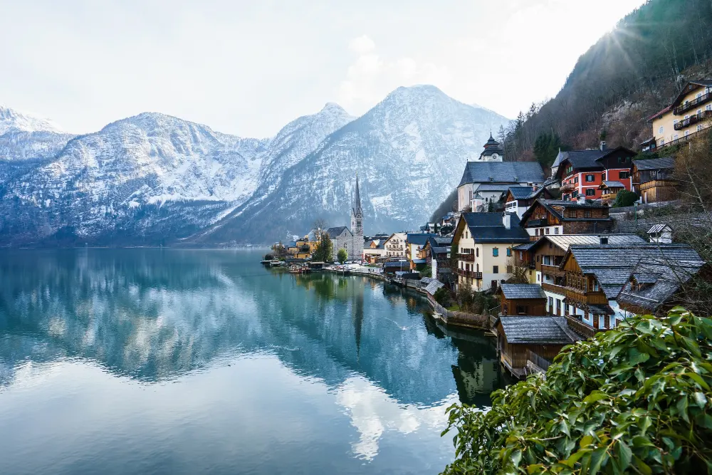 beautiful-shot-small-village-surrounded-by-lake-snowy-hills