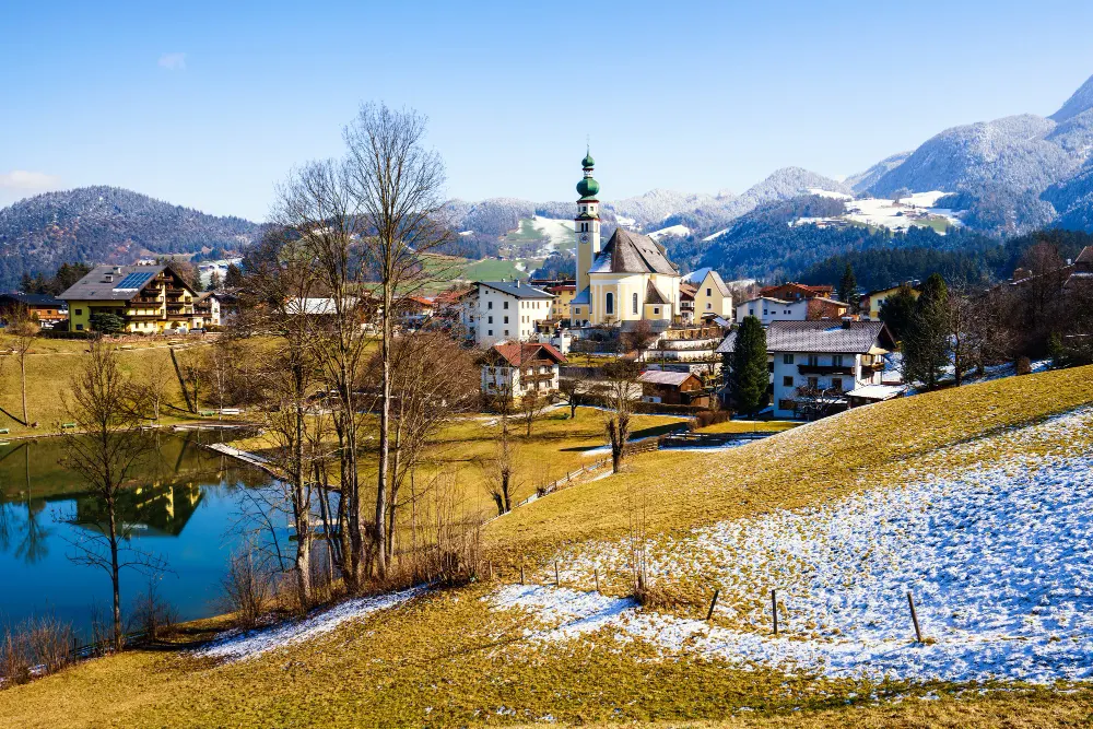 beautiful-shot-small-village-surrounded-by-lake-snowy-hills(1)