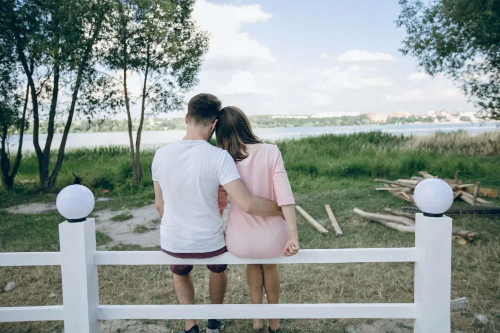 couple-backs-sitting-white-fence