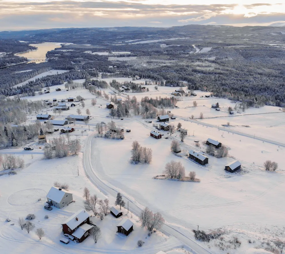 high-angle-shot-town-covered-snow-surrounded-by-forests-lake-cloudy-sky