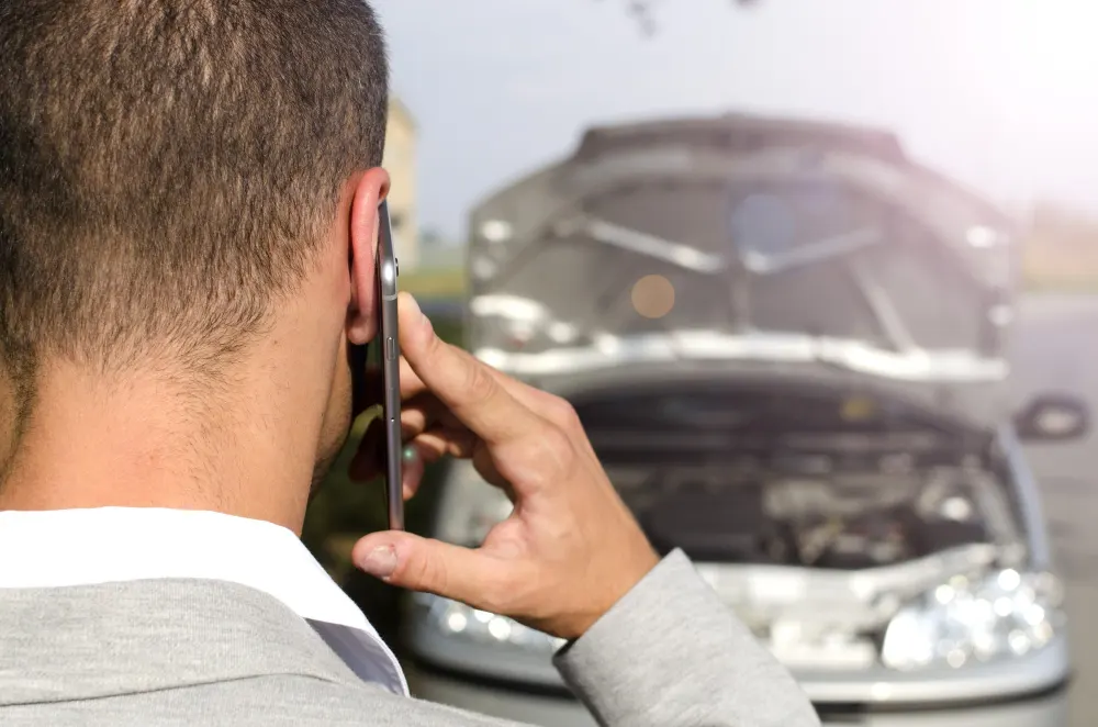 man-standing-by-broken-vehicle-calling-tow-service