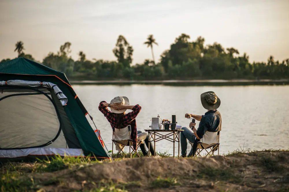 rear-view-young-backpacker-couple-sitting-relax-front-tent-near-lake-with-coffee-set-making-fresh-coffee-grinder-while