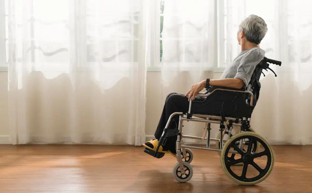 shot-senior-man-looking-out-window-while-sitting-wheelchair