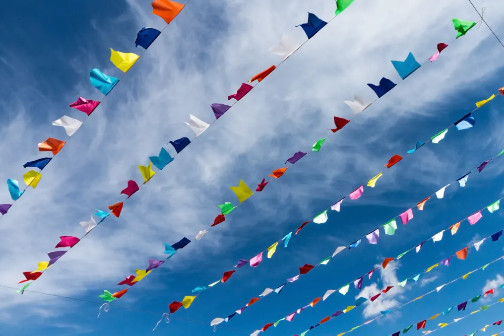 small-cute-colorful-flags-rope-hanging-outside-holiday-with-bright-blue-sky-white-clouds-background-italy-sardinia