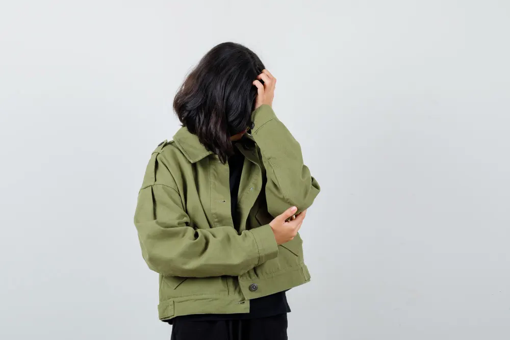 teen-girl-leaning-head-hand-t-shirt-green-jacket-looking-sad-front-view