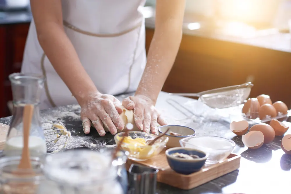 unrecognizable-woman-standing-kitchen-table-kneading-dough-by-hand