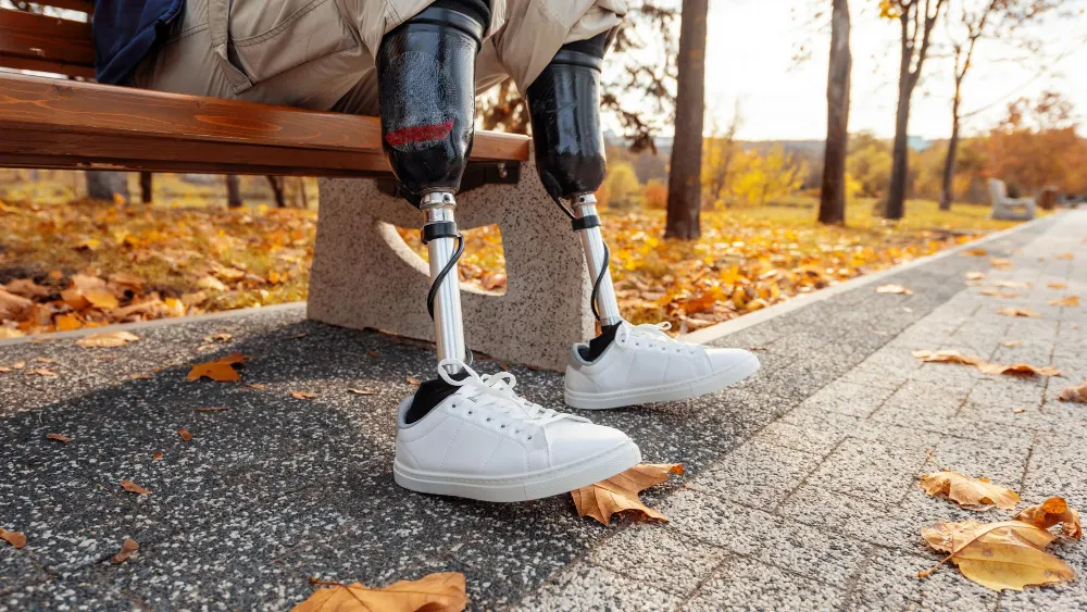 view-man-with-prosthetic-legs-white-sneakers-sitting-bench-park