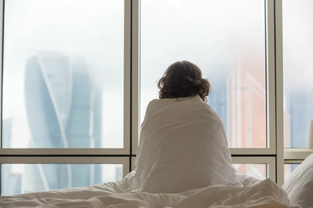 woman-sitting-bed-looking-through-window