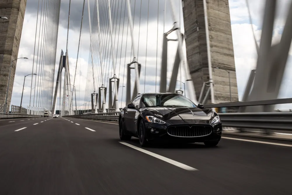 black-sedan-car-driving-on-the-bridge-road