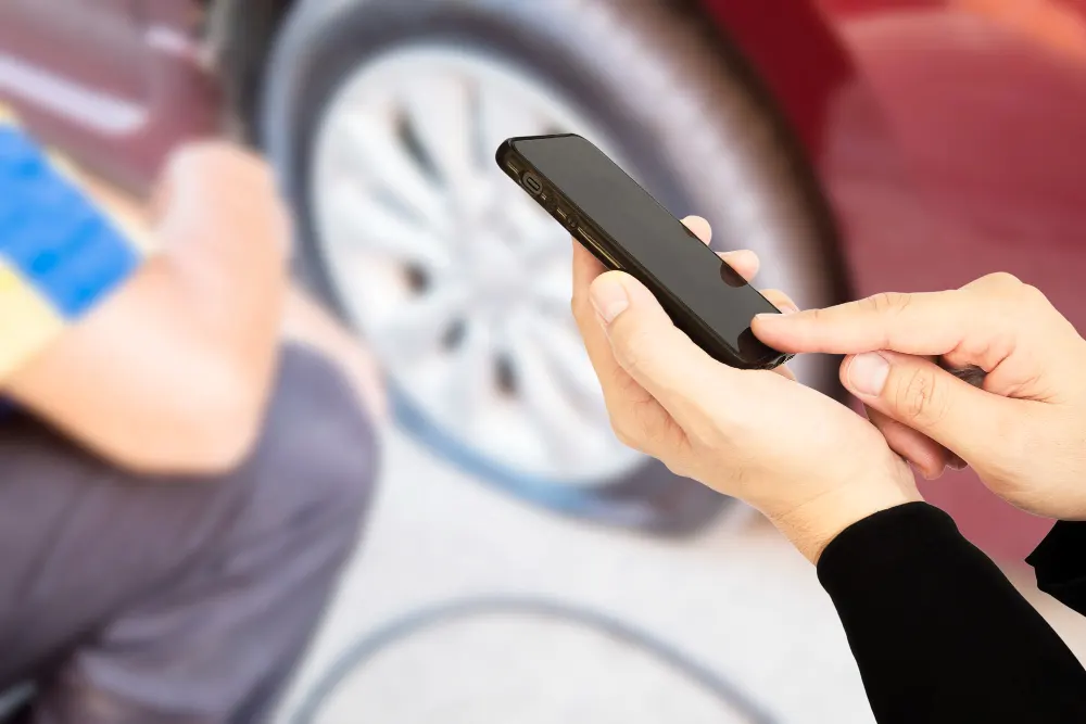 man-is-using-mobile-phone-calling-somebody-over-car-flat-tire-background