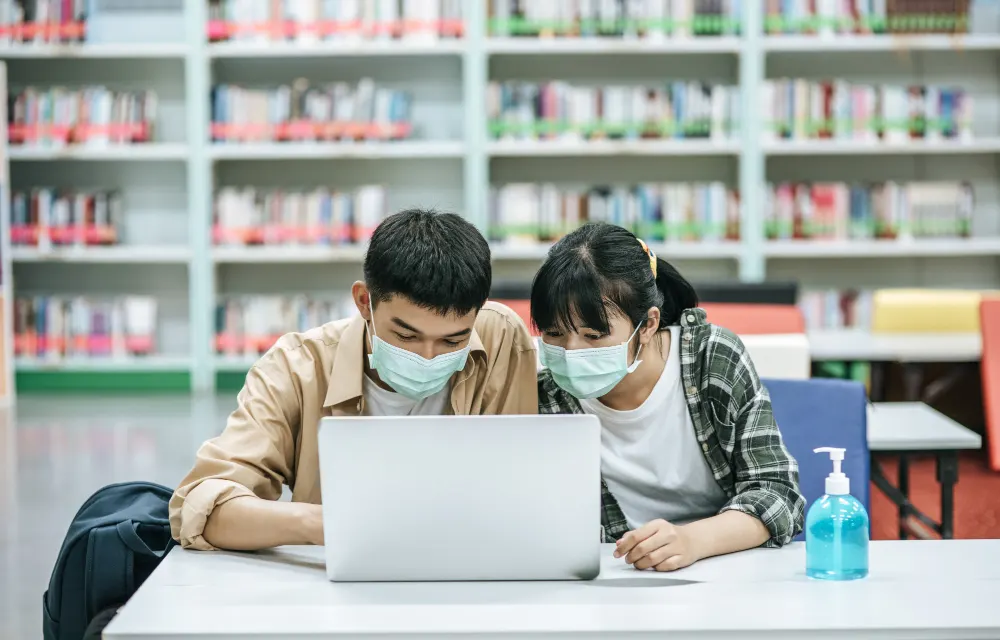 men-and-women-wear-masks-and-use-a-laptop to-search-for-books-in-the-library