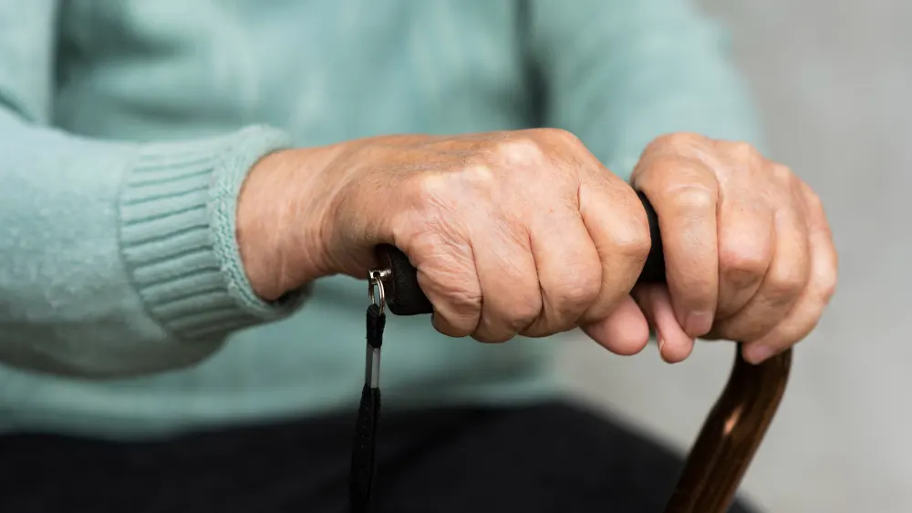 older-woman-holding-cane-in-hands