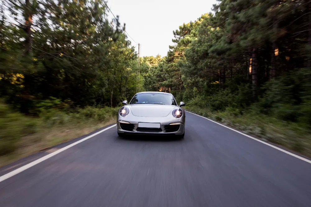 silver-color-coupe-with-front-lightson-the-road