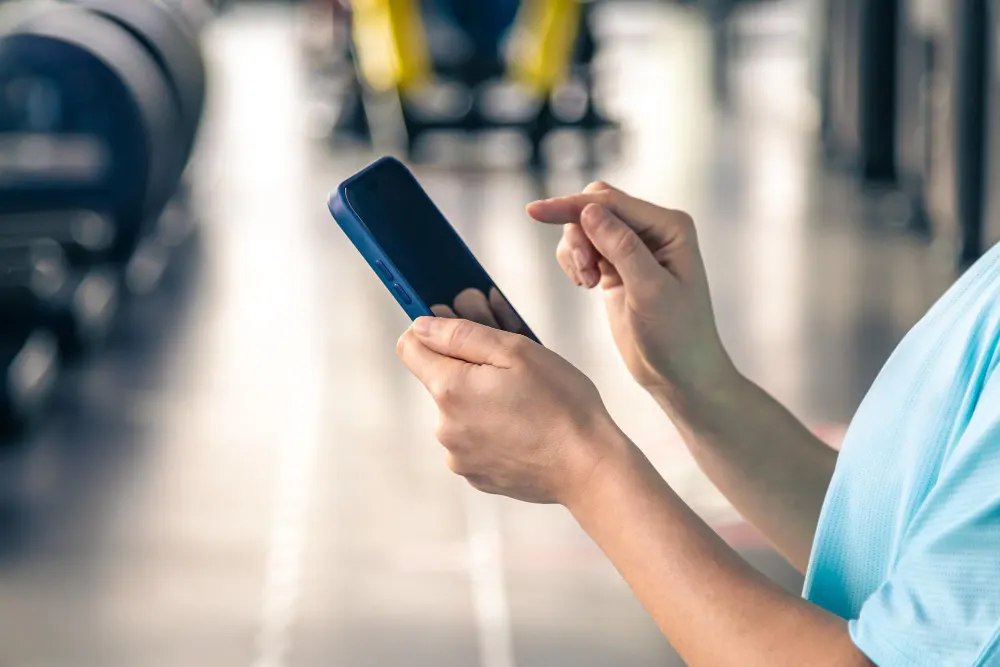 woman-using-smartphone-in-fitness-gym-close-up