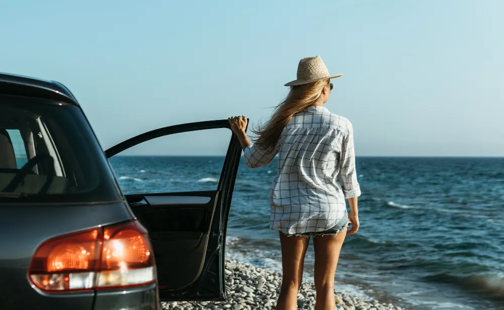 mid-shot-woman-looking-sea-by-car