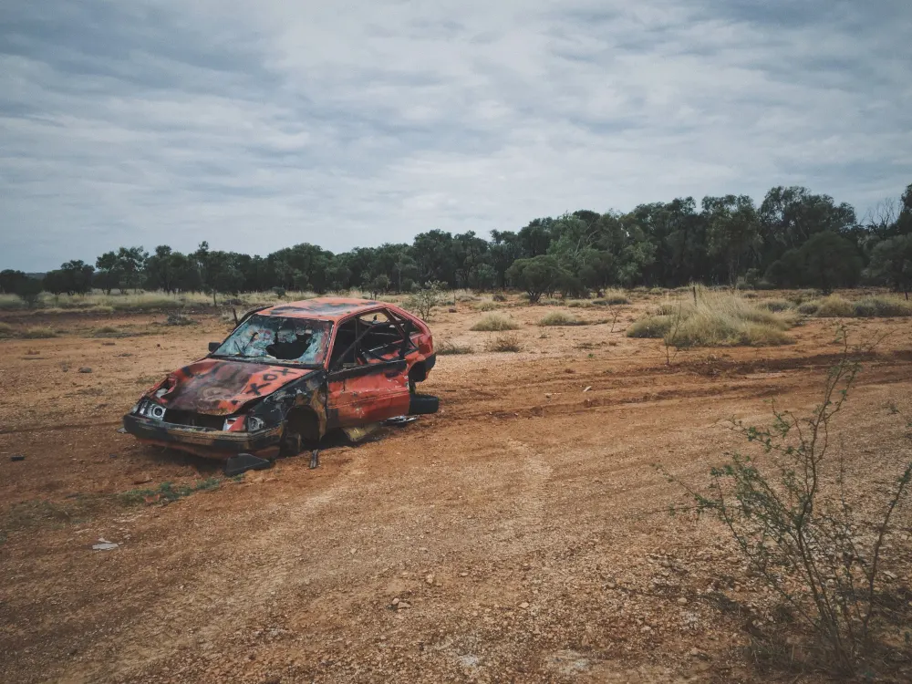 old-broken-up-car-dry-grass-field-with-trees