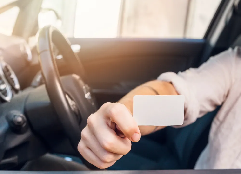 man-showing-business-card-in-car