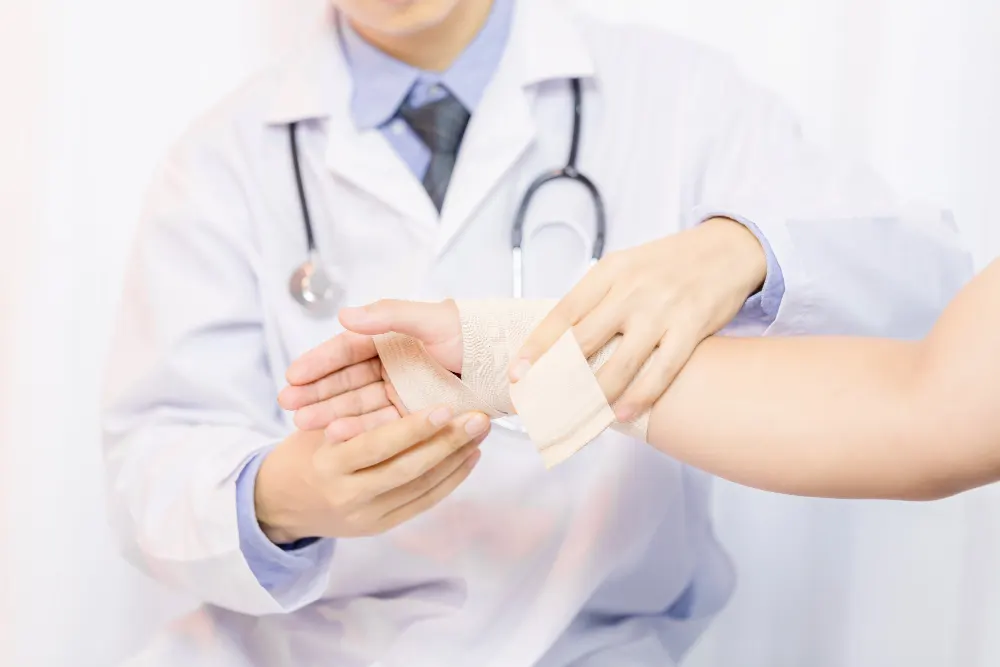 male-doctor-putting-gauze-on-young-man's-hand-in-clinic