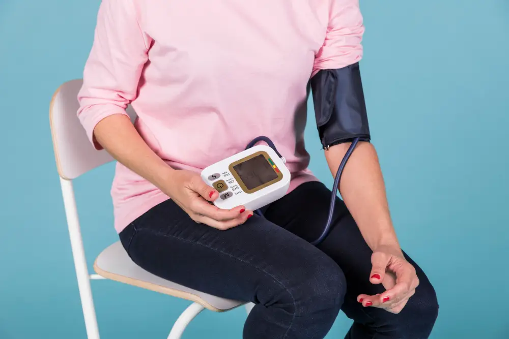 Woman-sitting-on-chair-checking-blood-pressure-on-electric-tonometer