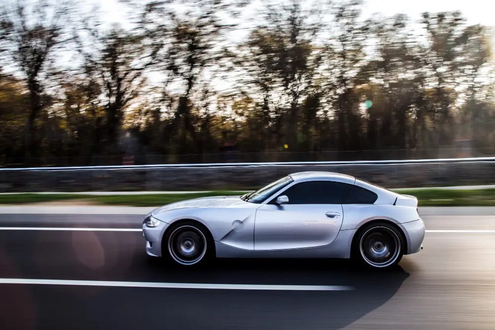 Metallic-color-coupe-driving-by-the-forest